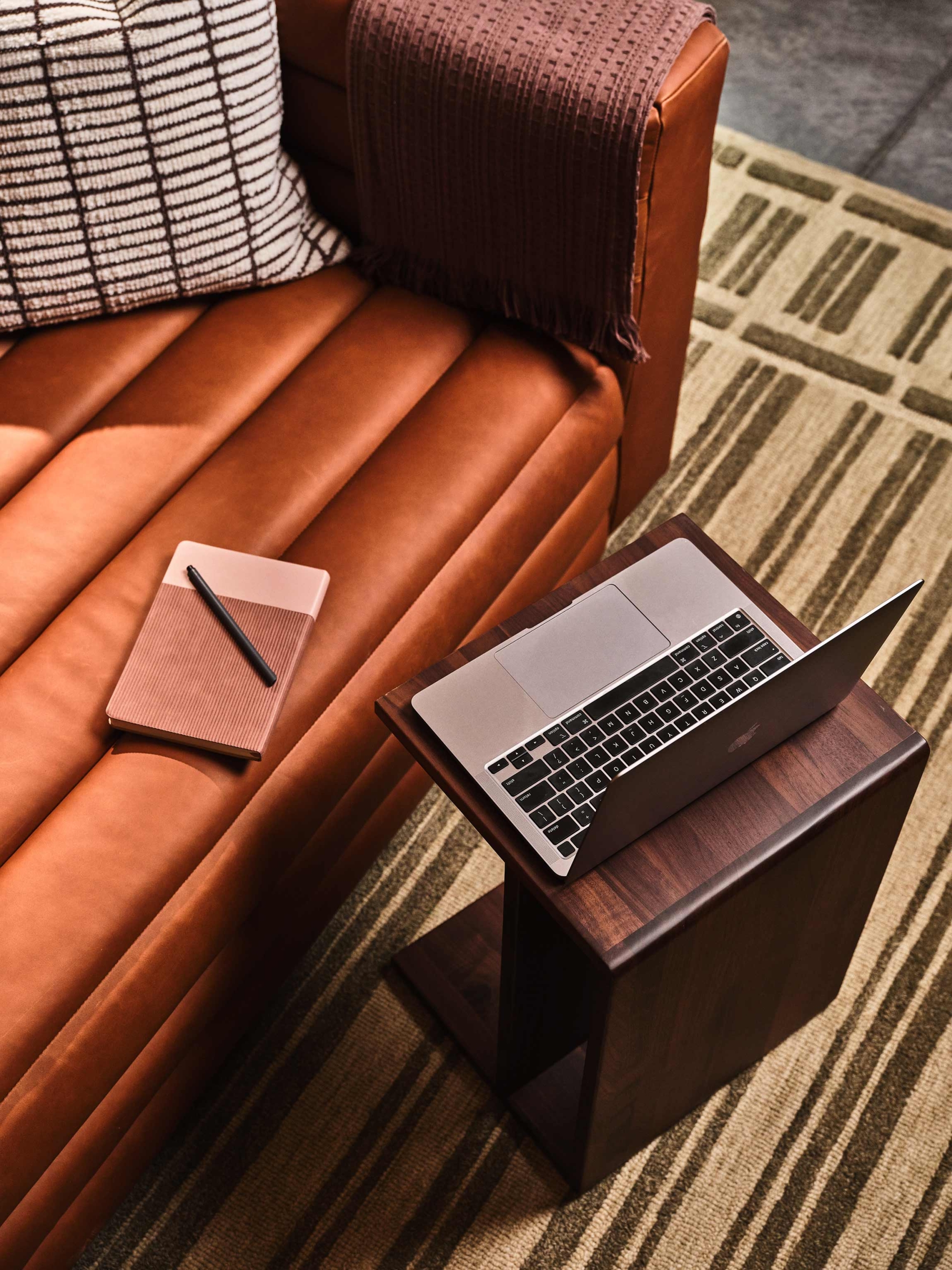 Notebook on couch with laptop on a side table